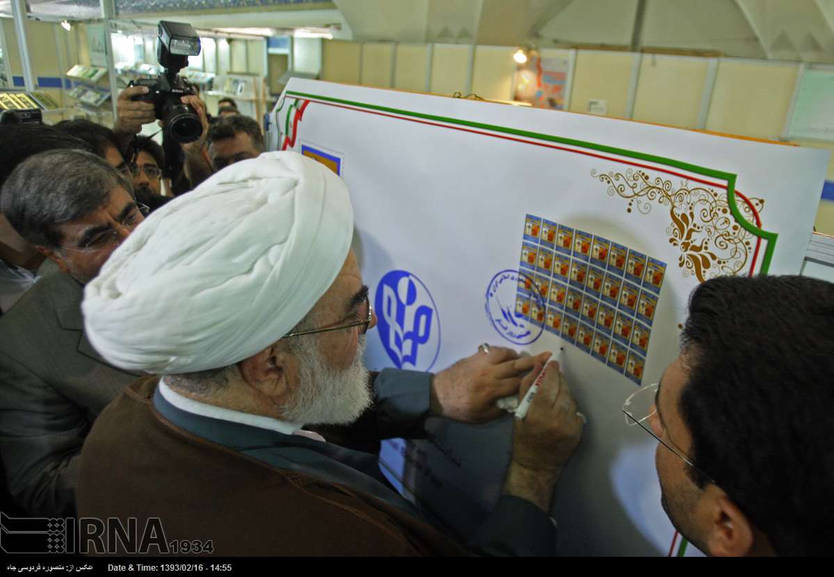 記念切手にサインするゴルパーイェガーニー師(最高指導者事務所長)