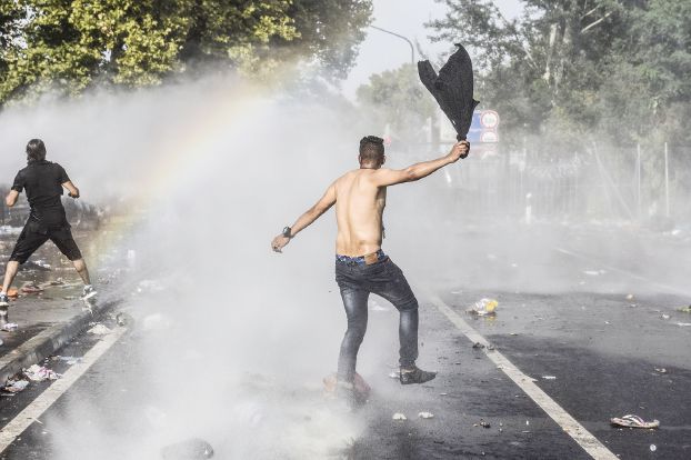 セルビア国境付近でハンガリー警察に対向する二人の難民(AFP)