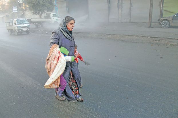 アレッポ爆撃の後、子どもを抱きかかえるシリア人女性（AFP）