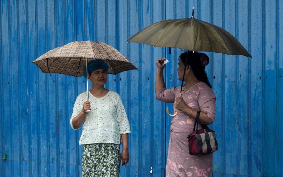 2025年7月、ヤンゴン市内でバスを待ちながら会話している女性2人（AFP)